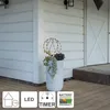 A decorative sphere with lights sits in a planter on a wooden porch next to a white door. Produktbild-Vorschau