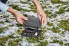 A person is installing a Gardena winter protection box for cables in a snowy garden. Produktbild-Vorschau