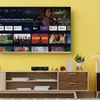 A television displaying a streaming service interface, placed above a media console in a living room setting. Produktbild-Vorschau
