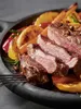 A close-up shot of sliced steak with roasted potatoes and bell peppers on a dark plate. Produktbild-Vorschau