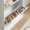 A white shoe cabinet with several pairs of shoes stored inside. Some shoes are on shelves, and one drawer is pulled out, revealing more shoes. Produktbild-Vorschau