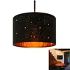 A black pendant lamp with a star pattern and a gold interior, shown against a white background. A smaller inset image shows the lamp hanging in a dining area. Anteprima dell’immagine prodotto