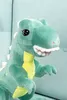 Close-up of a green plush dinosaur toy with yellow accents on its chest and white spikes on its back. Produktbild-Vorschau