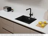 A black kitchen sink with a black faucet is shown on a white countertop, with a toaster and a jar to the left, and lemons on a cutting board to the right. Podgląd zdjęcia produktu