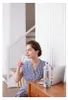 A woman is sitting at a desk and drinking from a bottle. Produktbild-Vorschau
