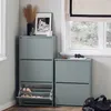 A corner of a room with two gray shoe cabinets, one taller than the other, next to a window with a Roman blind. Decorative items and shoes are visible. Náhled obrázku produktu