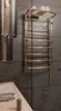 A gold electric towel warmer mounted on a dark tiled wall in a bathroom. Podgląd zdjęcia produktu