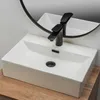 A white rectangular vessel sink with a black faucet is shown on a wooden countertop, with a round mirror reflecting the sink and faucet. Náhľad obrázku produktu