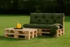 A pallet sofa and coffee table set with cushions and a blanket on a grassy lawn. Anteprima dell’immagine prodotto