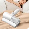 A white cordless vacuum cleaner is placed on a beige fabric surface next to a person sleeping on a white pillow and beige bedding. Náhľad obrázku produktu
