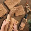 Hands wrapping a bottle in honeycomb paper packaging on a wooden surface with other wrapped gifts and cinnamon sticks. Produktbild-Vorschau