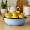 A light blue enamel bowl filled with pears sits on a wooden countertop, with a teapot and a canister in the background. Podgląd zdjęcia produktu