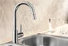 A modern kitchen sink faucet with a pull-down sprayer, set against a textured wall. There are also glasses and a pitcher of water on the countertop. Náhľad obrázku produktu