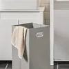 A close-up of a gray laundry basket with a beige towel draped over the side, set in a bathroom environment. Produktbild-Vorschau