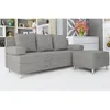A gray sofa with an ottoman is shown in a room with shelves and a dresser in the background. Náhled obrázku produktu