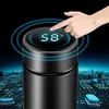 A hand is touching the LED display of a black smart thermobecher, which shows the temperature as 58°C. The background features a blurred circuit board pattern. Náhľad obrázku produktu