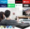 A couple watching TV while holding a remote, with a streaming box in the foreground and app logos at the top. Produktbild-Vorschau