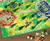 A colorful board game with a fantasy theme, featuring a winding path through a green landscape with houses, trees, and a castle. Podgląd zdjęcia produktu