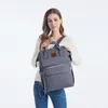 A woman is holding a gray backpack. Produktbild-Vorschau