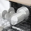 A dishwasher rack filled with clean white plates and bowls. Produktbild-Vorschau