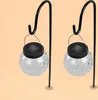 Two solar-powered hanging lanterns with cracked glass globes are displayed on black metal stands against a light orange background. Produktbild-Vorschau
