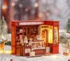 A miniature Christmas-themed dessert shop display, set in a snowy environment with decorative trees and festive lights. Podgląd zdjęcia produktu