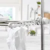 A close-up view of a white shoe and white socks drying on a multi-tiered drying rack. Produktbild-Vorschau