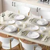 A dining table set for four people with plates, bowls, cutlery, and napkins, in a kitchen setting. Produktbild-Vorschau