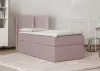 A pink box spring bed with a headboard is shown in a room with a bookshelf and a chair. Produktbild-Vorschau