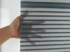 A hand is holding a piece of fabric with horizontal stripes. Produktbild-Vorschau