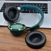 A pair of headphones with one earpad removed, resting on a laptop keyboard and a wooden surface. Podgląd zdjęcia produktu