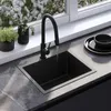 A modern kitchen sink with a black faucet and a black sink, set against a marble countertop and a window with white flowers. Produktbild-Vorschau