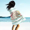A person standing on a beach, wrapped in a blanket with a Pusheen cat design. Produktbild-Vorschau