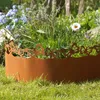 A close-up of a rusty metal garden border with a butterfly design, set in a garden with grass and flowers. Produktbild-Vorschau
