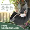 A person relaxing in a hanging chair on a balcony with plants and a railing. Produktbild-Vorschau