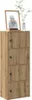 A tall, narrow wooden cabinet with four doors, topped with a framed picture and a vase with greenery. Produktbild-Vorschau
