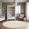 A nursery room with a crib, a built-in bed, a rocking chair, and a round rug with a sheep design. Produktbild-Vorschau