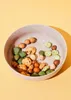 A close-up shot of a bowl filled with assorted rice crackers. Produktbild-Vorschau