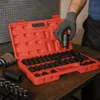 A person's gloved hand is holding a socket wrench attachment over an open red toolbox filled with socket wrenches. Anteprima dell’immagine prodotto
