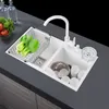 A white double kitchen sink with a faucet, a dish rack with vegetables, and dishes being washed. Podgląd zdjęcia produktu