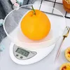A digital kitchen scale with an orange in a glass bowl is displayed. Voir les images du produit