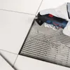 A gloved hand is using a Bosch oscillating multi-tool to remove grout between tiles. Podgląd zdjęcia produktu
