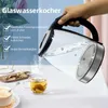 A hand pouring hot water from a glass kettle into a teacup, with text overlays highlighting product features. Produktbild-Vorschau