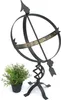 A black metal sundial with Roman numerals on a white background, next to a small potted green plant. Anteprima dell’immagine prodotto