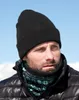 A man wearing a black beanie and a patterned neck gaiter in a snowy, outdoor environment. Anteprima dell’immagine prodotto