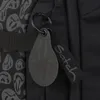 A close-up view of a black backpack with a smiley face keychain and a branded strap. Produktbild-Vorschau