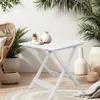 A white folding table is set up on a patio or balcony, surrounded by plants and decorative vases. Anteprima dell’immagine prodotto