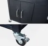 A close-up view of a black outdoor grill storage cart, showing the cabinet doors with handles and a caster wheel with a brake. Anteprima dell’immagine prodotto