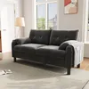 A gray sofa is placed in a living room setting with a floor lamp and a window in the background. Produktbild-Vorschau