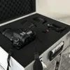 A camera and lenses are neatly arranged in a silver case with foam inserts. Produktbild-Vorschau
